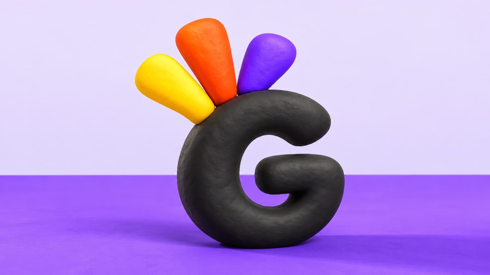 The Greeto G mark sculpted in clay on a lilac and violet tabletop